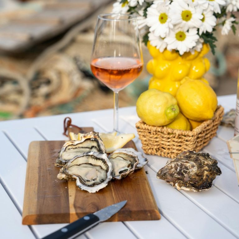 Plateau d'huîtres avec un verre de rosé et des citrons sur une table en extérieur. Plateau d'huîtres avec un verre de rosé et des citrons sur une table en extérieur.